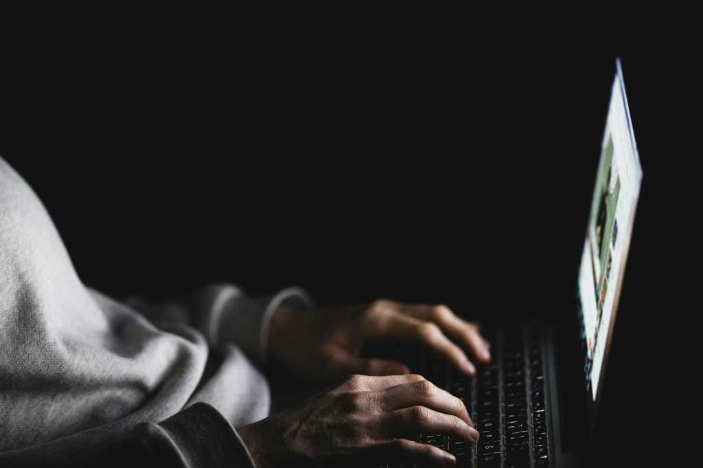 Anonymous woman using laptop in darkness